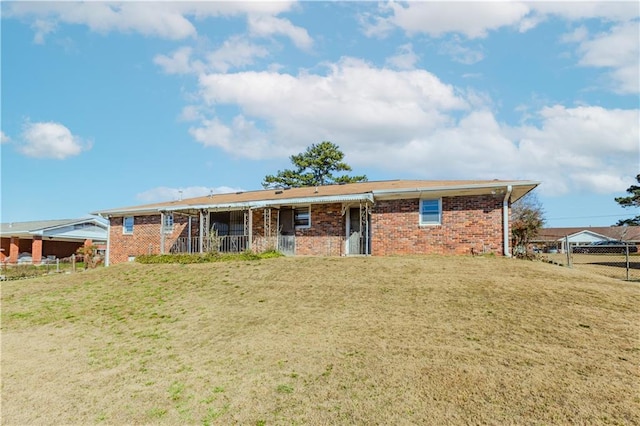 view of front of home featuring brick siding, a front lawn, and fence