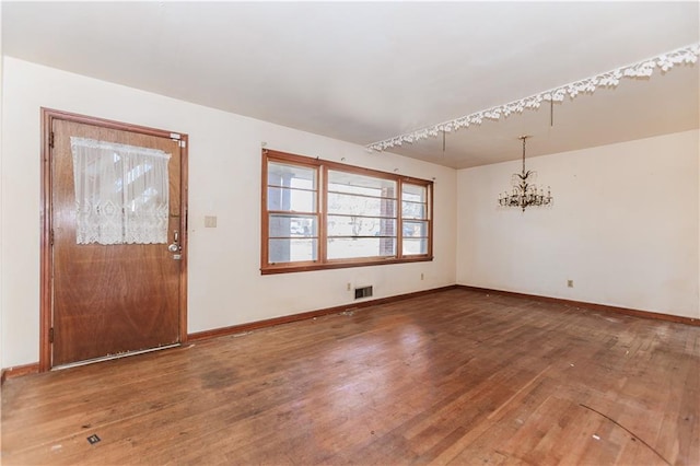 interior space with an inviting chandelier, baseboards, visible vents, and hardwood / wood-style floors