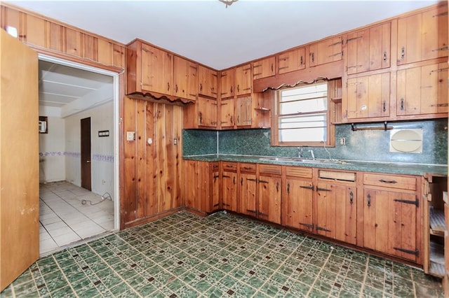 kitchen featuring tasteful backsplash, brown cabinetry, and dark countertops