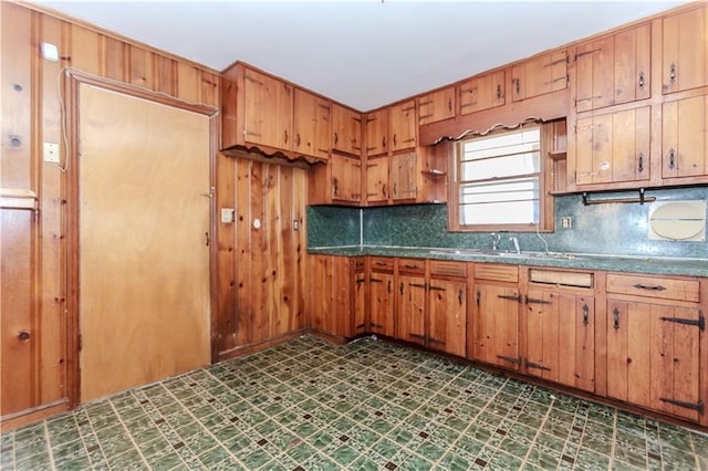 kitchen featuring tasteful backsplash, dark floors, brown cabinets, and dark countertops