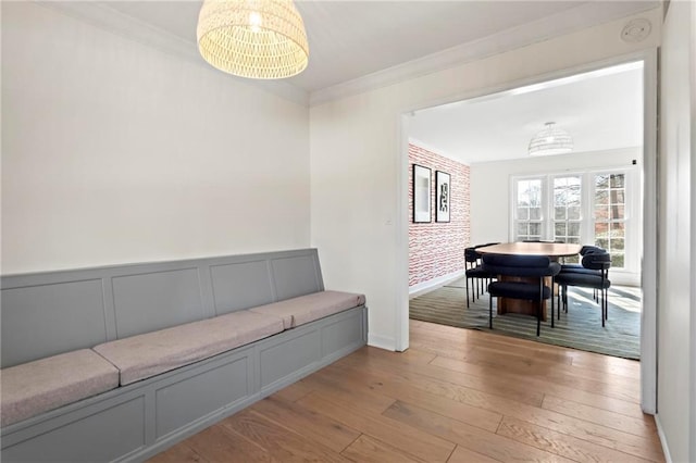 sitting room with crown molding, brick wall, and light hardwood / wood-style floors