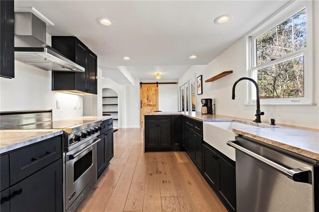 5371 Tall Oak Dr, Marietta, GA 30068 - kitchen featuring wall chimney range hood, appliances with stainless steel finishes, a barn door, a sink, and dark cabinetry