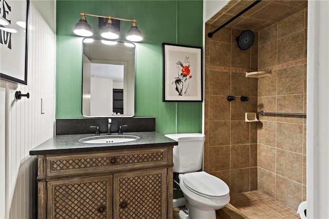 bathroom featuring vanity, toilet, and a tile shower