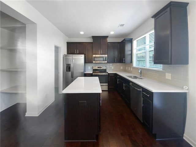 kitchen featuring backsplash, sink, dark hardwood / wood-style floors, a kitchen island, and stainless steel appliances