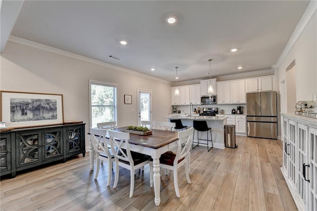 dining room featuring ornamental molding, sink, and light hardwood / wood-style floors