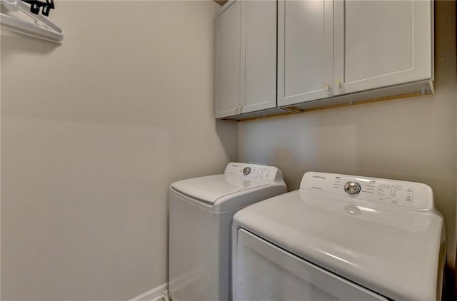 clothes washing area featuring cabinets and separate washer and dryer