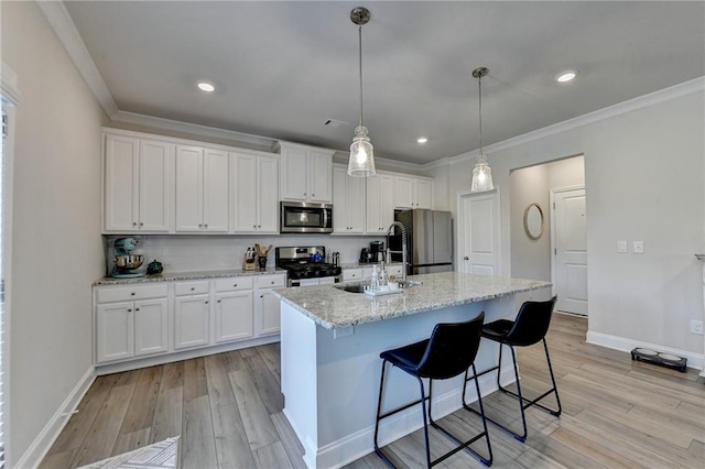 kitchen with appliances with stainless steel finishes, white cabinetry, an island with sink, and light hardwood / wood-style floors