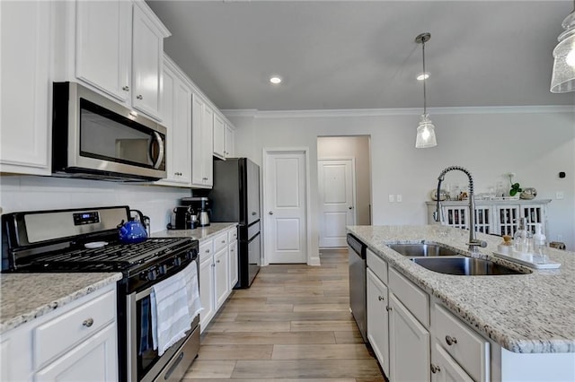 kitchen featuring white cabinets, hanging light fixtures, light hardwood / wood-style flooring, stainless steel appliances, and a kitchen island with sink