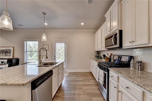 kitchen with an island with sink, stainless steel appliances, decorative light fixtures, and light wood-type flooring