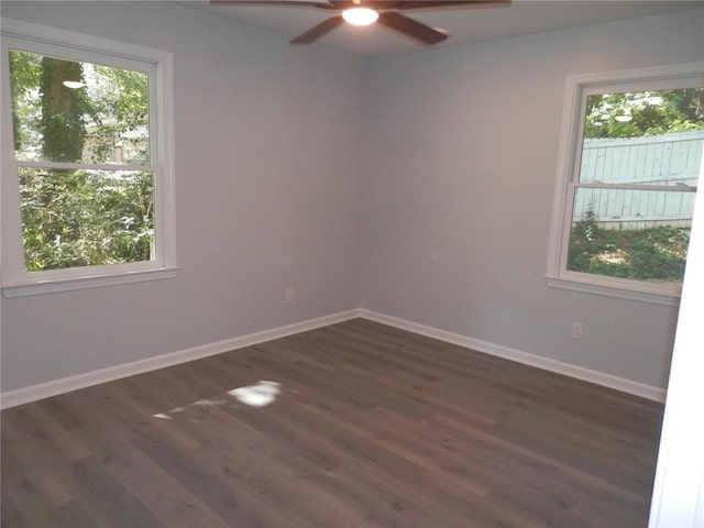 empty room with a healthy amount of sunlight, ceiling fan, and dark hardwood / wood-style flooring