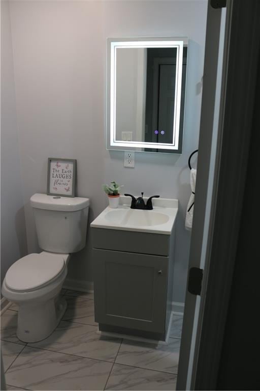 bathroom featuring vanity, toilet, baseboards, and marble finish floor