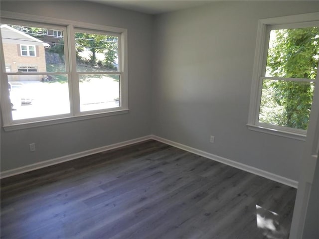 spare room with a healthy amount of sunlight and dark wood-type flooring