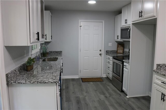 kitchen with white cabinetry, light stone counters, stainless steel appliances, and sink