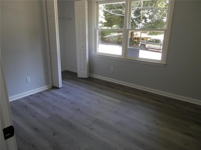 unfurnished bedroom with dark wood-type flooring and a closet