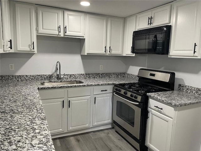 kitchen with white cabinetry, stainless steel range with gas stovetop, black microwave, and a sink