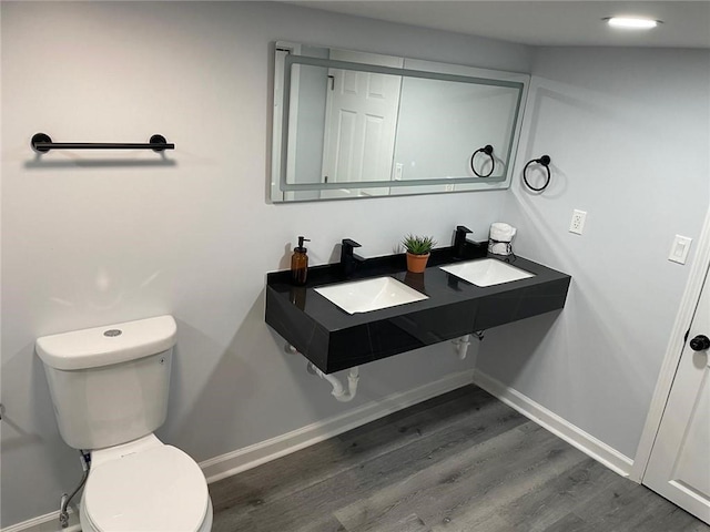 bathroom featuring toilet, wood-type flooring, and sink