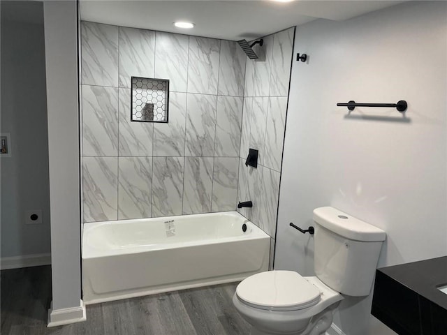 bathroom featuring baseboards, toilet, wood finished floors, and bathtub / shower combination