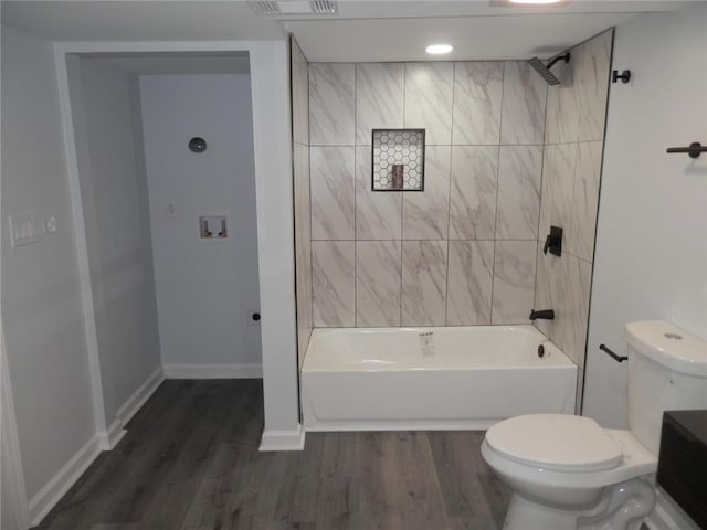 bathroom with hardwood / wood-style floors, tiled shower / bath, and toilet