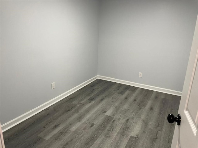 unfurnished room with dark wood finished floors and baseboards