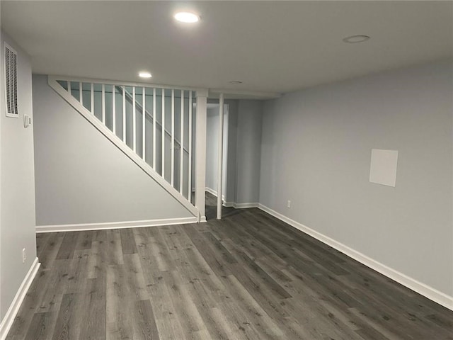 finished below grade area featuring dark wood finished floors, stairs, recessed lighting, and baseboards