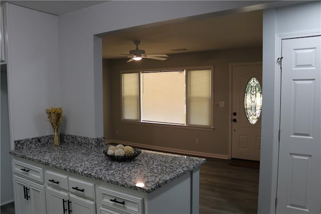 kitchen with dark wood-type flooring, ceiling fan, light stone counters, and white cabinets