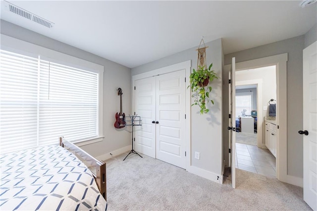 bedroom featuring light carpet, baseboards, visible vents, and a closet