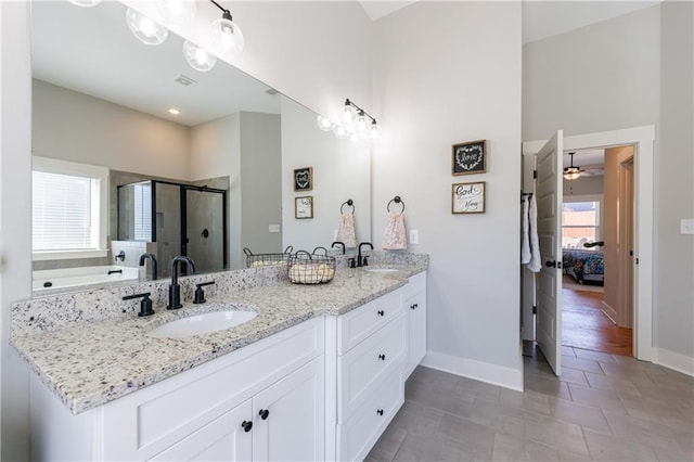 ensuite bathroom featuring connected bathroom, a sink, a shower stall, and baseboards