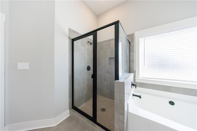 bathroom featuring a stall shower, tile patterned flooring, baseboards, and a garden tub