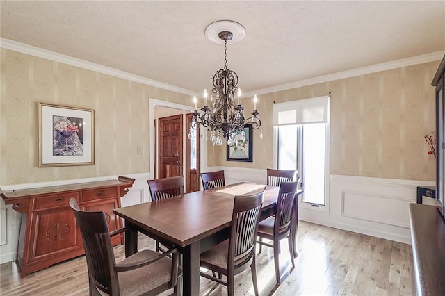 dining area featuring a textured ceiling, crown molding, a notable chandelier, and light wood-type flooring