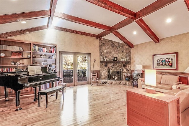 interior space featuring vaulted ceiling with beams, light hardwood / wood-style floors, and a stone fireplace