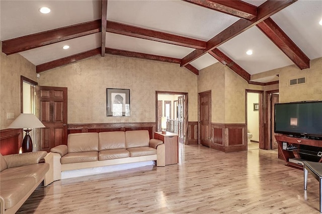 living room featuring lofted ceiling with beams and light hardwood / wood-style flooring