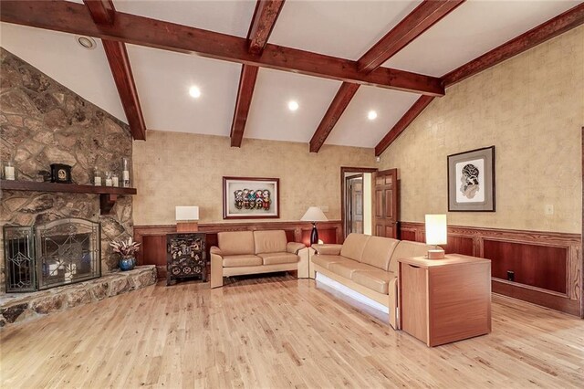 living room with a fireplace, vaulted ceiling with beams, and light hardwood / wood-style flooring