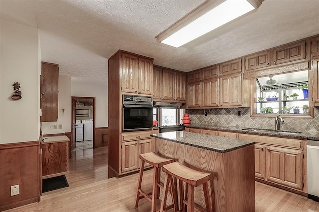 kitchen featuring a kitchen breakfast bar, oven, light hardwood / wood-style floors, washer and clothes dryer, and a kitchen island