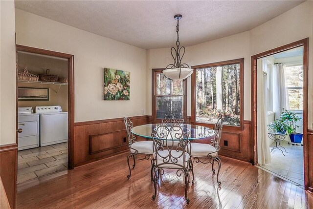 dining area with separate washer and dryer, wood walls, wood-type flooring, and a textured ceiling