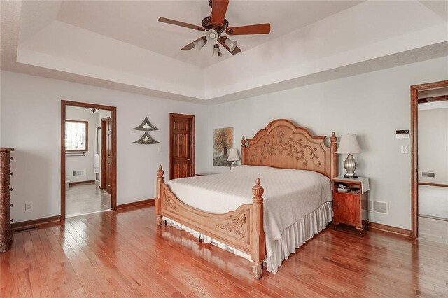 bedroom with wood-type flooring, a tray ceiling, and ceiling fan