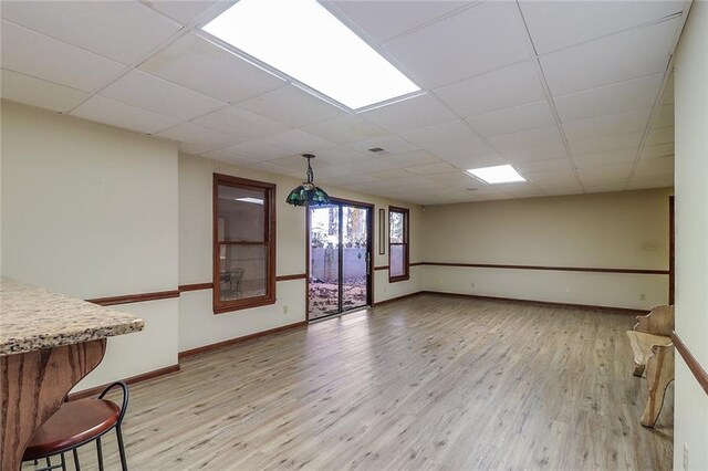 unfurnished living room featuring light wood-type flooring and a paneled ceiling