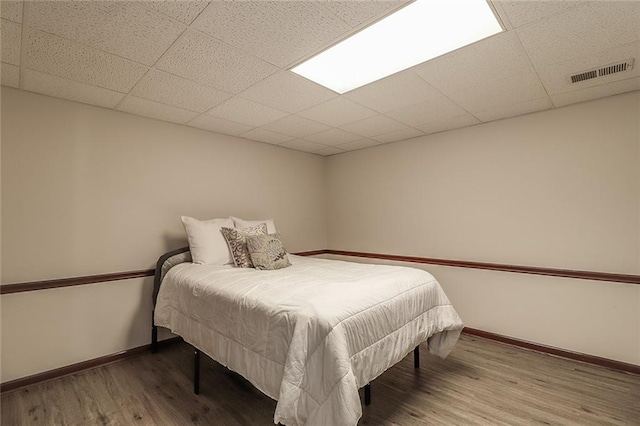 bedroom with hardwood / wood-style flooring and a paneled ceiling