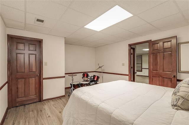 bedroom featuring light hardwood / wood-style flooring and a drop ceiling