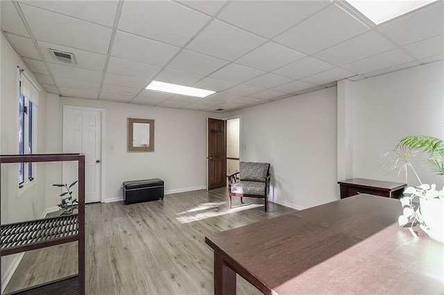 office area with a paneled ceiling and light hardwood / wood-style flooring