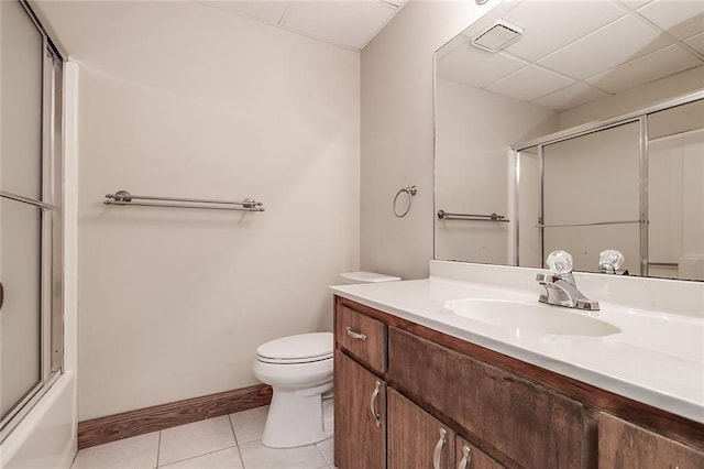 full bathroom featuring a paneled ceiling, tile patterned floors, bath / shower combo with glass door, vanity, and toilet