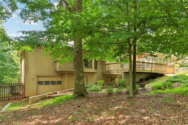 back of property with a wooden deck and a garage