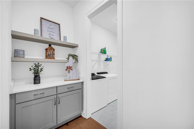 bar with gray cabinets, washer and clothes dryer, and light wood-type flooring