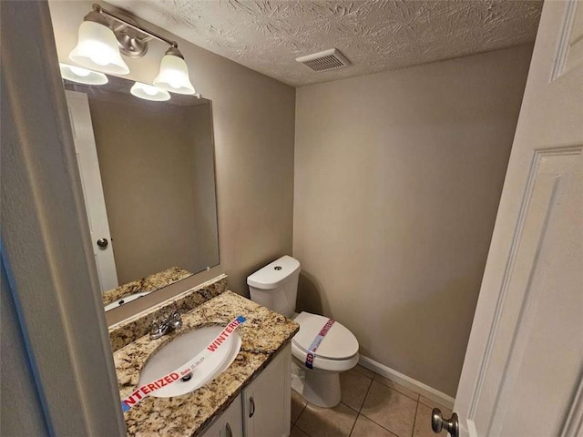 bathroom with a textured ceiling, tile patterned floors, vanity, and toilet