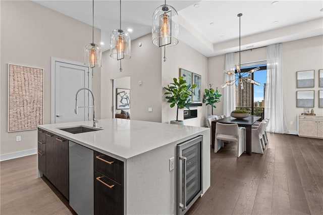 kitchen with beverage cooler, dishwasher, wood-type flooring, an island with sink, and sink