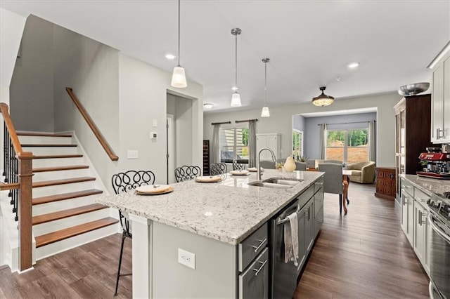 kitchen featuring a kitchen island with sink, gray cabinets, stainless steel appliances, sink, and decorative light fixtures