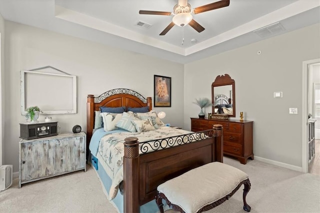 carpeted bedroom featuring ceiling fan and a tray ceiling