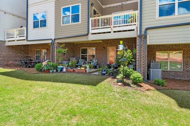 back of house with a balcony, a patio area, and a lawn