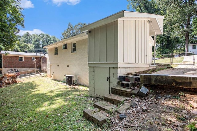 view of property exterior with central AC and a yard