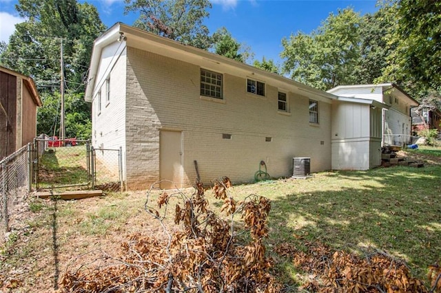 rear view of house with central air condition unit and a yard