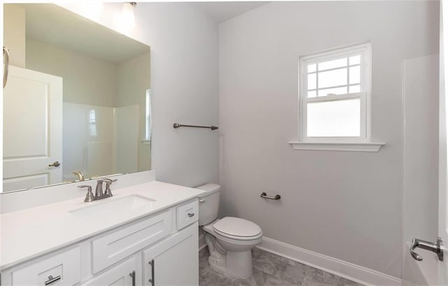 bathroom featuring toilet, baseboards, walk in shower, and vanity